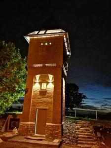 una torre de ladrillo alta con una puerta y luces en ella en Logement insolite La tour de Larbuisson, en Herve