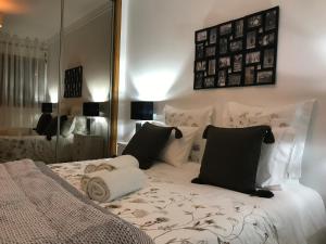 a bed with black and white pillows and a mirror at Miguel Torga Apartments in Coimbra