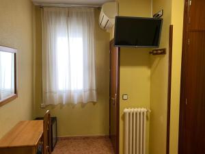 ein Zimmer mit einem Fernseher und einer Tür mit einem Fenster in der Unterkunft Hostal Internacional in Madrid + 30 Fotos