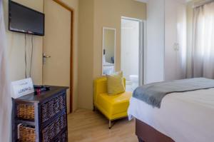 a bedroom with a bed and a yellow chair at Seroloana Guest House in Rustenburg