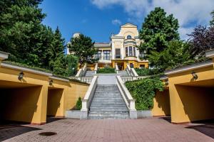 a large yellow house with stairs in front at Parkhotel Brno in Brno