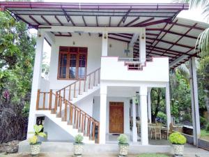 a white house with stairs and a porch at Ruins View Holiday Resort in Polonnaruwa