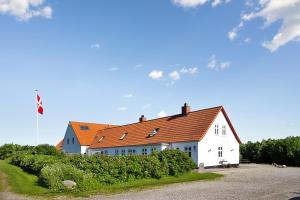 un grand bâtiment blanc avec un toit orange dans l'établissement Klitgaarden, à Hjørring