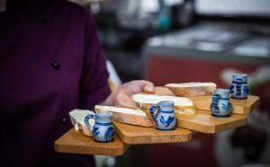 a person holding a tray with bread and blue cups at Landgasthof Brunnenwirt Zum Meenzer in Fischbachtal