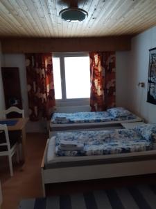 um quarto com três camas e uma mesa e uma janela em Matkakoti, Motel Kieppi Kuhmo em Kuhmo