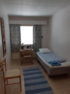 Schlafzimmer mit einem Bett, einem Schreibtisch und einem Fenster in der Unterkunft Matkakoti, Motel Kieppi Kuhmo in Kuhmo