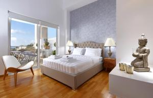 a bedroom with a bed and a chair and a balcony at Spacious Mint Luxury Villa access to Private Beach in Agia Pelagia +21 photos