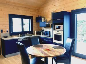 a kitchen with a table and chairs and blue cabinets at La KJOTTE avec option jacuzzi in Le Teich