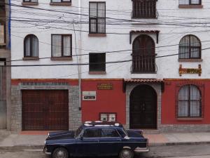 ein blaues Auto, das vor einem rot-weißen Gebäude parkt in der Unterkunft Hostal Bivouac in La Paz