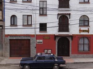 a blue car parked in front of a red and white building at Hostal Bivouac in La Paz
