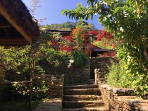 a stone path in a garden with flowers at Riepe Village in Lamjung