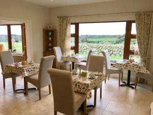 un comedor con mesas y sillas y una gran ventana en Mourne Country House Bed and Breakfast en Kilkeel