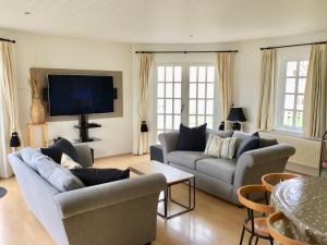 a living room with couches and a flat screen tv at Hello !! and welcome to Solius Lodge in South Cerney