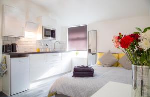 eine weiße Küche mit einem Bett und einer Vase aus Blumen in der Unterkunft Rock Salt Studios in Blackpool