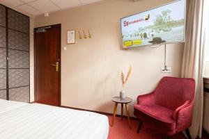 a hotel room with a couch, chair and television at Strandhotel Scheveningen in Scheveningen