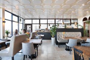a restaurant with tables and chairs and people in the background at Strandhotel Scheveningen in Scheveningen