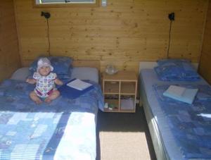 Un niño pequeño sentado en una cama en una habitación en Kiige Holiday Park, en Linnamäe