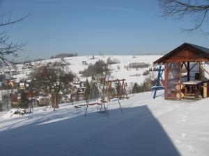 une aire de jeux dans la neige à côté d'un bâtiment dans l'établissement Gospodarstwo Agroturystyczne Handzlówka, à Skawa
