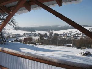 uma vista para um campo coberto de neve a partir de um alpendre em Gospodarstwo Agroturystyczne Handzlówka em Skawa