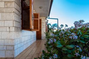 a building with a walkway next to a bush with purple flowers at Casa Vacanze Villa Chiara in San Vito