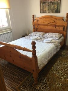 a bedroom with a wooden bed with white sheets at Apartment Sena in Sarajevo