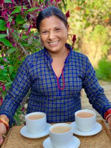 uma mulher sentada numa mesa com duas chávenas de café em Riepe Village em Ghanpokhara
