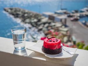 a red cake on a plate next to a glass of water at Vardia Bay Studios in Karavostasi