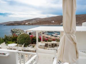 a patio with white chairs and an umbrella at Vardia Bay Studios in Karavostasi