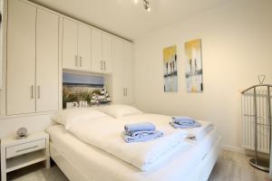 1 dormitorio blanco con armarios blancos y toallas en una cama en Villa Rossini Wohnung 2, en Wangerooge