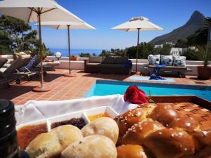 een dienblad met eten op een tafel naast een zwembad bij Diamond House Guesthouse in Kaapstad