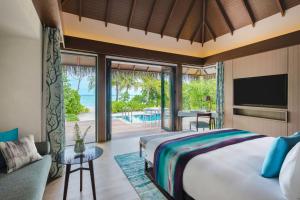 a bedroom with a large bed and a view of the ocean at Pullman Maldives All-Inclusive Resort in Maamutaa