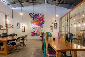 a room with tables and chairs and a wall with a painting at Socialtel Antigua in Antigua Guatemala