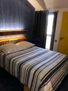 a bedroom with a bed with a striped blanket and a window at Le Relais d'Etagnac in Étagnac