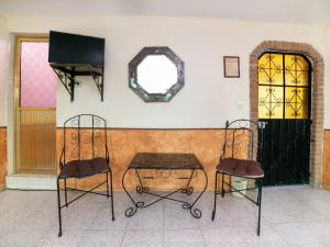 twee stoelen en een tafel en een spiegel aan een muur bij Hotel del Carmen in Tlalpujahua de Rayón