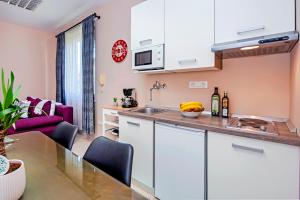 a kitchen with white cabinets and a table with chairs at Rovinj City Apartment in Rovinj