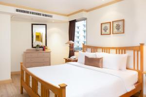 a bedroom with a large white bed and a dresser at Riverfront Bangkok in Bangkok