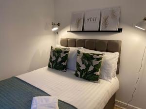 - une chambre avec un lit doté de draps blancs et d'oreillers verts dans l'établissement Womack Lodge, à St Helens