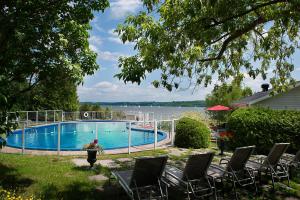 - une piscine avec des chaises et une vue sur l'eau dans l'établissement Goéliche hotel et appartement, à Saint-Laurent-de-l'ile d'Orleans