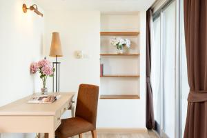 a white desk and chair in a room with a window at Riverfront Bangkok - SHA Extra Plus in Bangkok