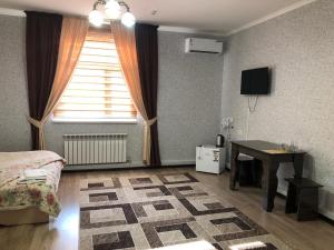 um quarto com uma cama, uma secretária e uma janela em Keruen em Taraz