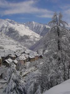 uma montanha coberta de neve com uma aldeia em primeiro plano em Gîtes du Presbytère em Saint-Dalmas-le-Selvage