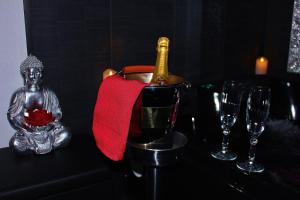 Una botella de champán en un cubo sobre una mesa con copas en The White Home Broadway Love Room en Châteauroux