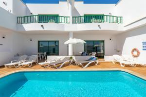 a villa with a swimming pool and a house at Apartamentos los Quiqueres in Puerto del Carmen