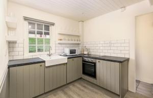 a white kitchen with a sink and a microwave at Fern Cottage in Killinaboy