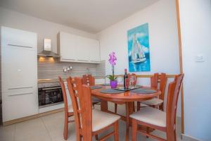 a kitchen with a wooden table and chairs in a kitchen at Apartmani Vesna Miliša in Primošten