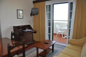 a living room with a couch and a tv and a table at Vila Marta in Funchal