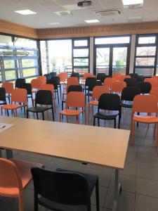 een leeg klaslokaal met oranje stoelen en tafels bij ibis Styles Vierzon in Vierzon