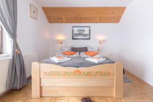 a bedroom with a wooden bed with orange pillows at Apartments Ukanc in Bohinj