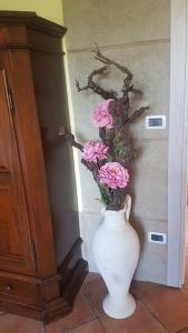 un vase blanc avec des fleurs roses dans le mur dans l'établissement Agriturismo Dinoabbo Apt, à Lucinasco
