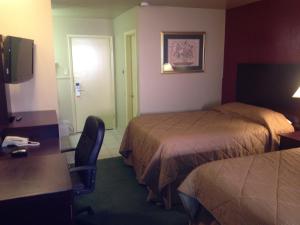 a hotel room with two beds and a desk and a chair at Colonial Inn Monahans TX in Monahans